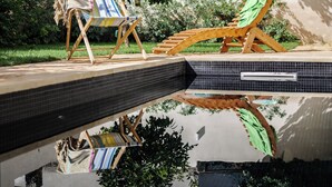 Un área junto a la piscina con sillones de descanso y una piscina con azulejos.