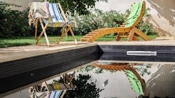 Un espace aménagé au bord de la piscine, avec des chaises longues et une piscine carrelée.