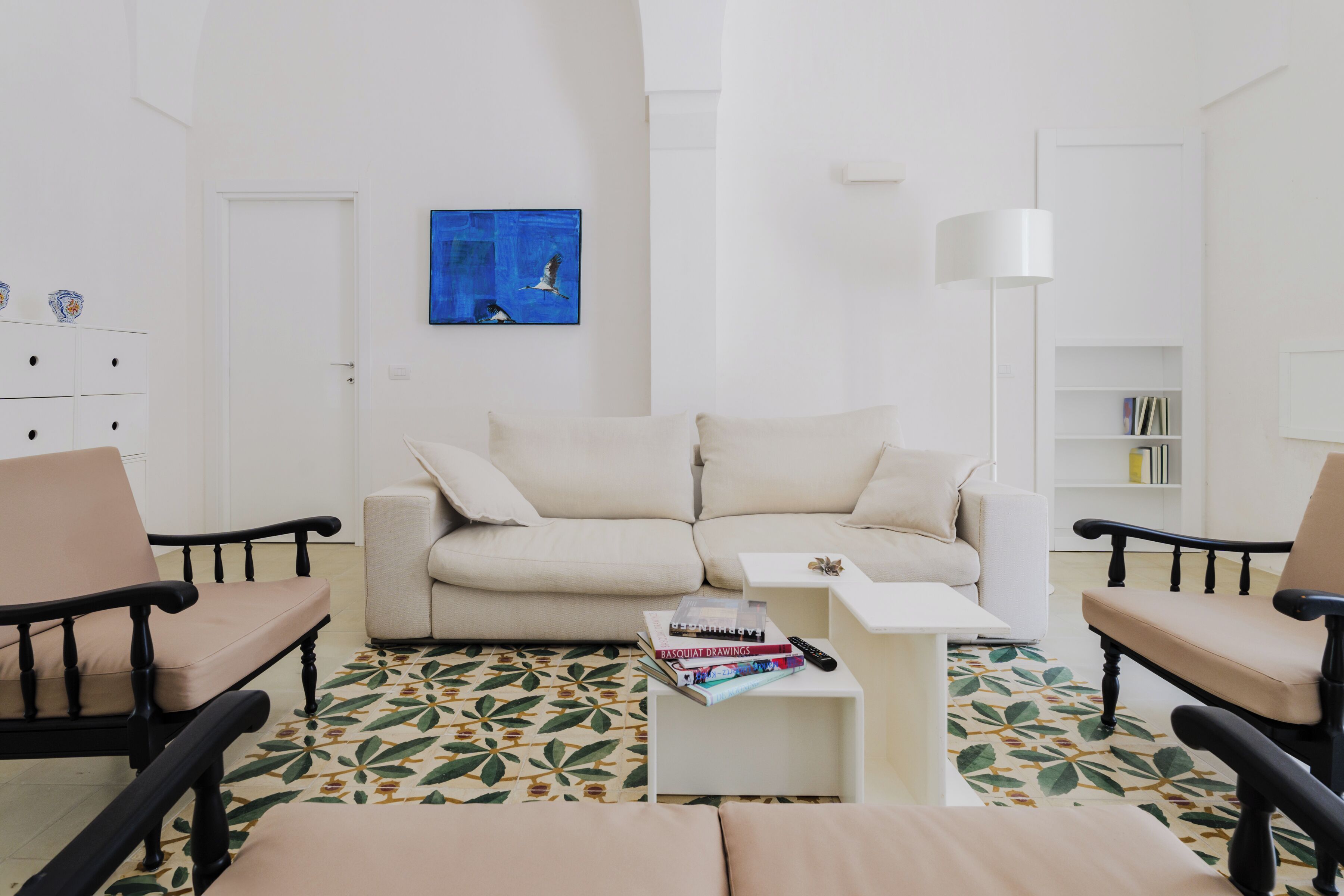 A living room with a beige sofa, two armchairs, a coffee table, and a patterned rug.
