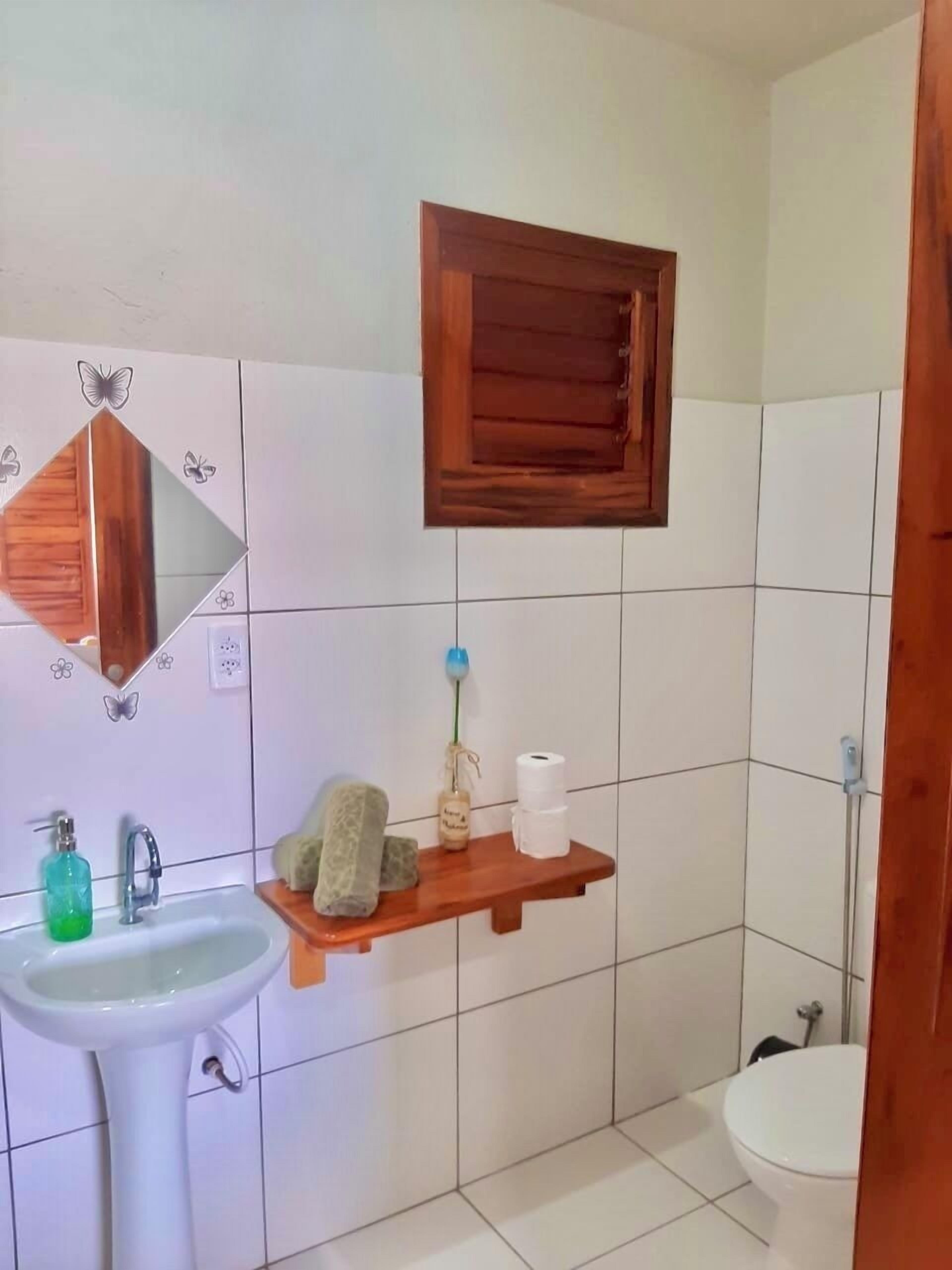 Een badkamer met een wastafel, spiegel, toilet en een houten plank met toiletartikelen.