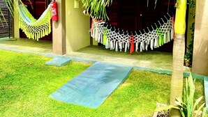 A building entrance with a hammock, a clothesline with hanging clothes, and a palm tree. - Pousada Areias de Flecheiras (Trairi)
