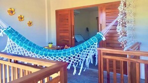 A hammock in a wooden room with a wooden door and a hanging floral decoration. - Pousada Areias de Flecheiras (Trairi)