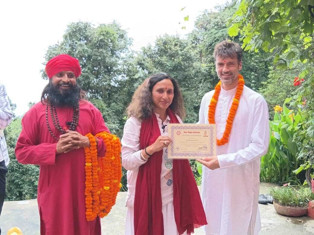 Three individuals holding a framed certificate outdoors with greenery in the background.