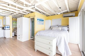 A bedroom with a bed, a dresser, a wardrobe, and an air conditioning unit.
