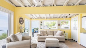 A living room with a large window, a sofa set, a coffee table, and a decorative clock. - Sunsets over Long Island Sound Peace and Tranquility 
Monthly Rentals Available  (Calverton)