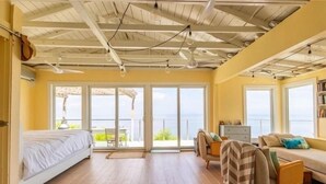 A spacious room with a bed, a sofa, and a chair, with large windows offering a view of the sea. - Sunsets over Long Island Sound Peace and Tranquility 
Monthly Rentals Available  (Calverton)