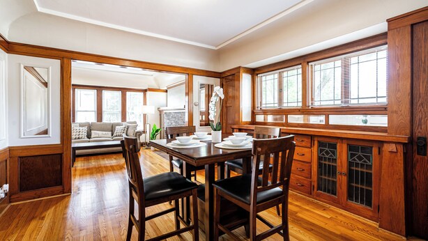 Un comedor con mesa y sillas de madera, un mueble empotrado con puertas de vidrio y vistas al exterior.