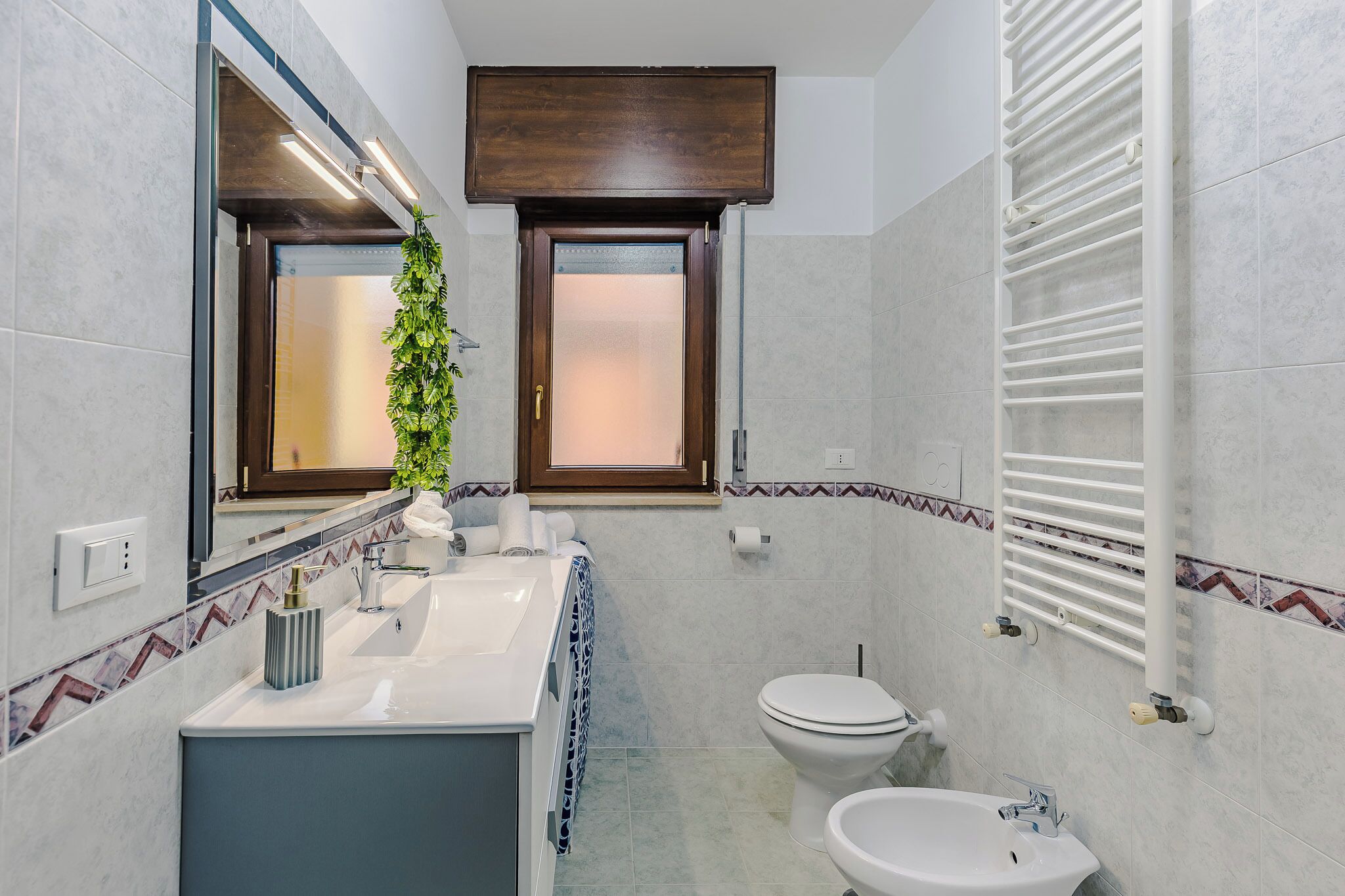 Un bagno moderno con uno specchio grande, un lavandino, un water e un porta asciugamani.