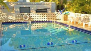A swimming pool with clear lane dividers, a lounge area with chairs, and a poolside umbrella. - 🌴 TROPICAL RETREAT 🌴 RV In The Keys (Big Pine Key)