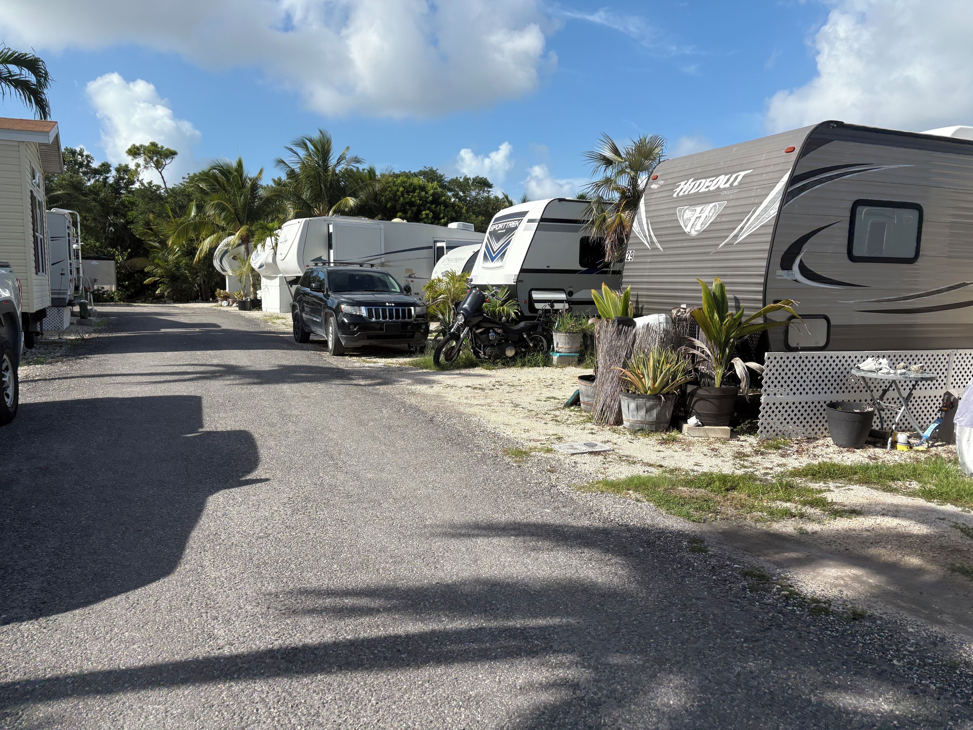 A caravan park with multiple RVs and a Jeep parked on a gravel road.