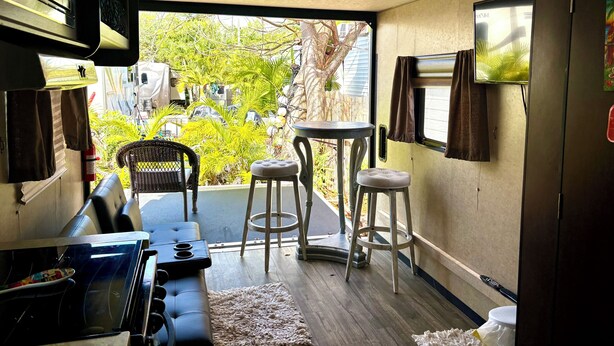 A compact RV interior with a kitchenette, seating area, and a view of the outdoors. - 🌴 TROPICAL RETREAT 🌴 RV In The Keys (Big Pine Key)