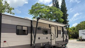 A Grey Wolf RV with a sliding door, two windows, and a small table with chairs. - 🌴 TROPICAL RETREAT 🌴 RV In The Keys (Big Pine Key)