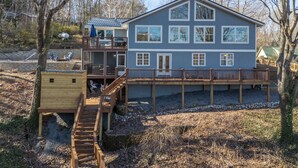 Ein zweistöckiges Haus mit einer Terrasse, einer kleinen Holzkonstruktion und einem Weg zum Haus.