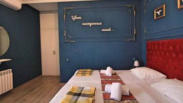Een hotelkamer met een bed, een rood hoofdeinde, een wandspiegel en een decoratief plaquette.