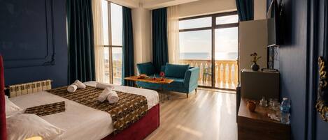 A hotel room with a bed, a desk, a chair, a balcony with a view, and a chandelier.