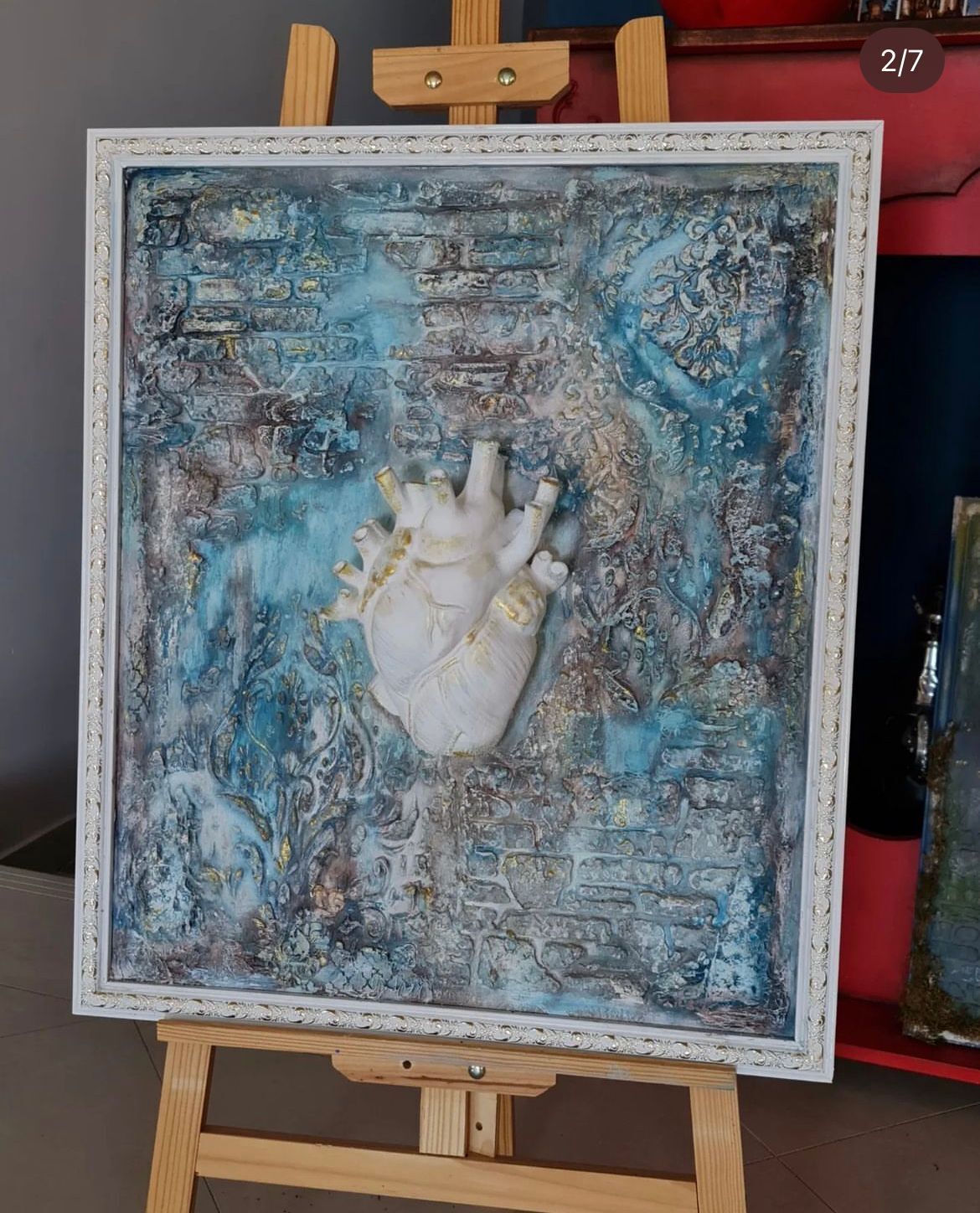 Un'opera d'arte incorniciata con un motivo a cuore esposta su un cavalletto.