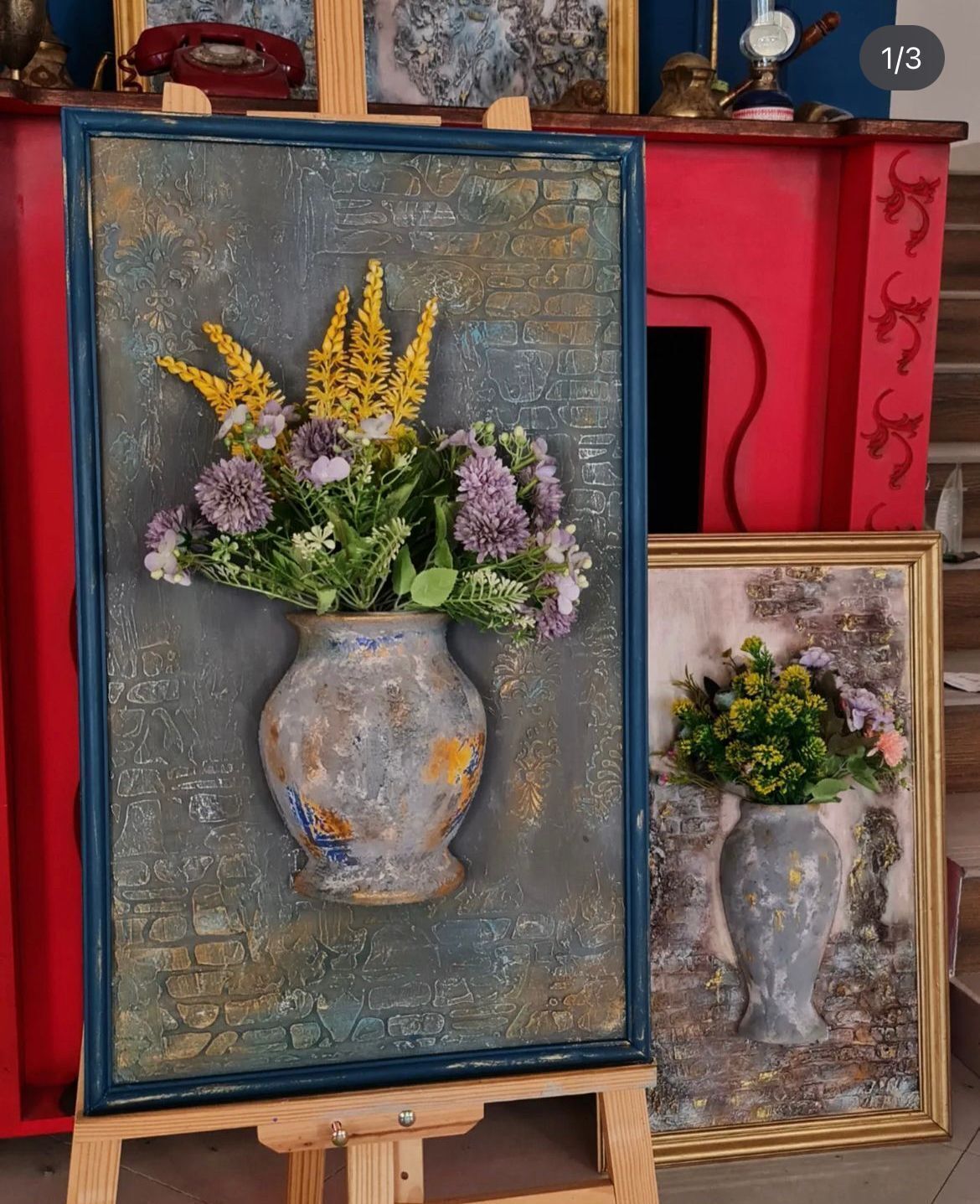 A framed painting of a vase with flowers on an easel.