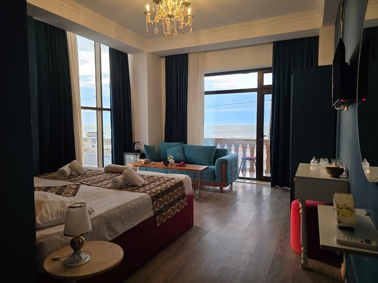 A hotel room with a bed, a sofa, a table, and a balcony with a view.