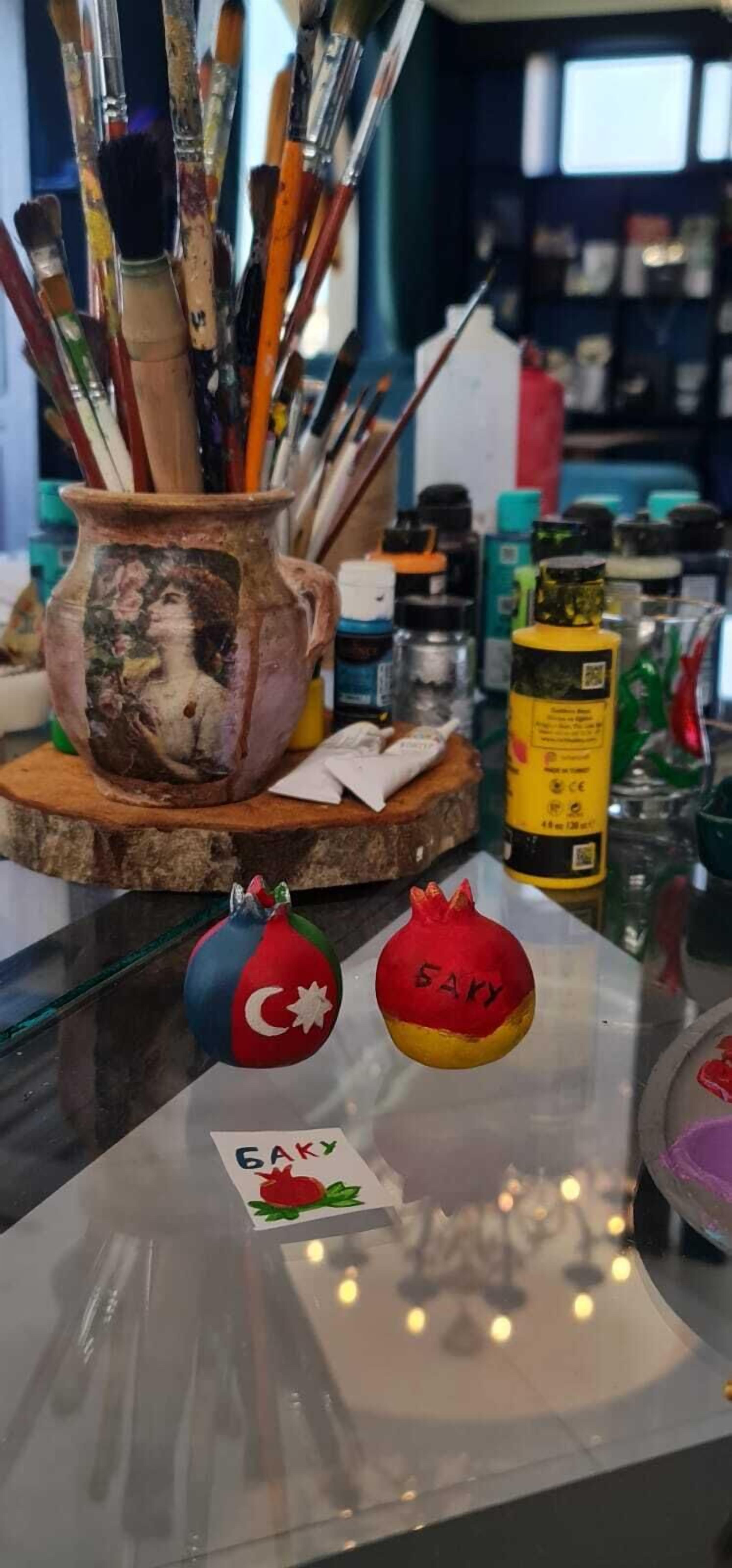 Ein Tisch mit einem Keramiktopf, Pinsel und Granatapfel-Dekorationen.