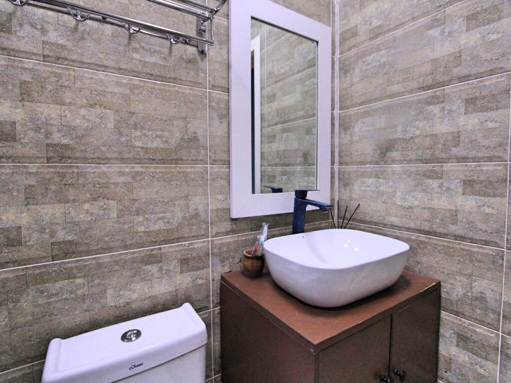 Un baño con lavamanos blanco, un espejo y un inodoro.