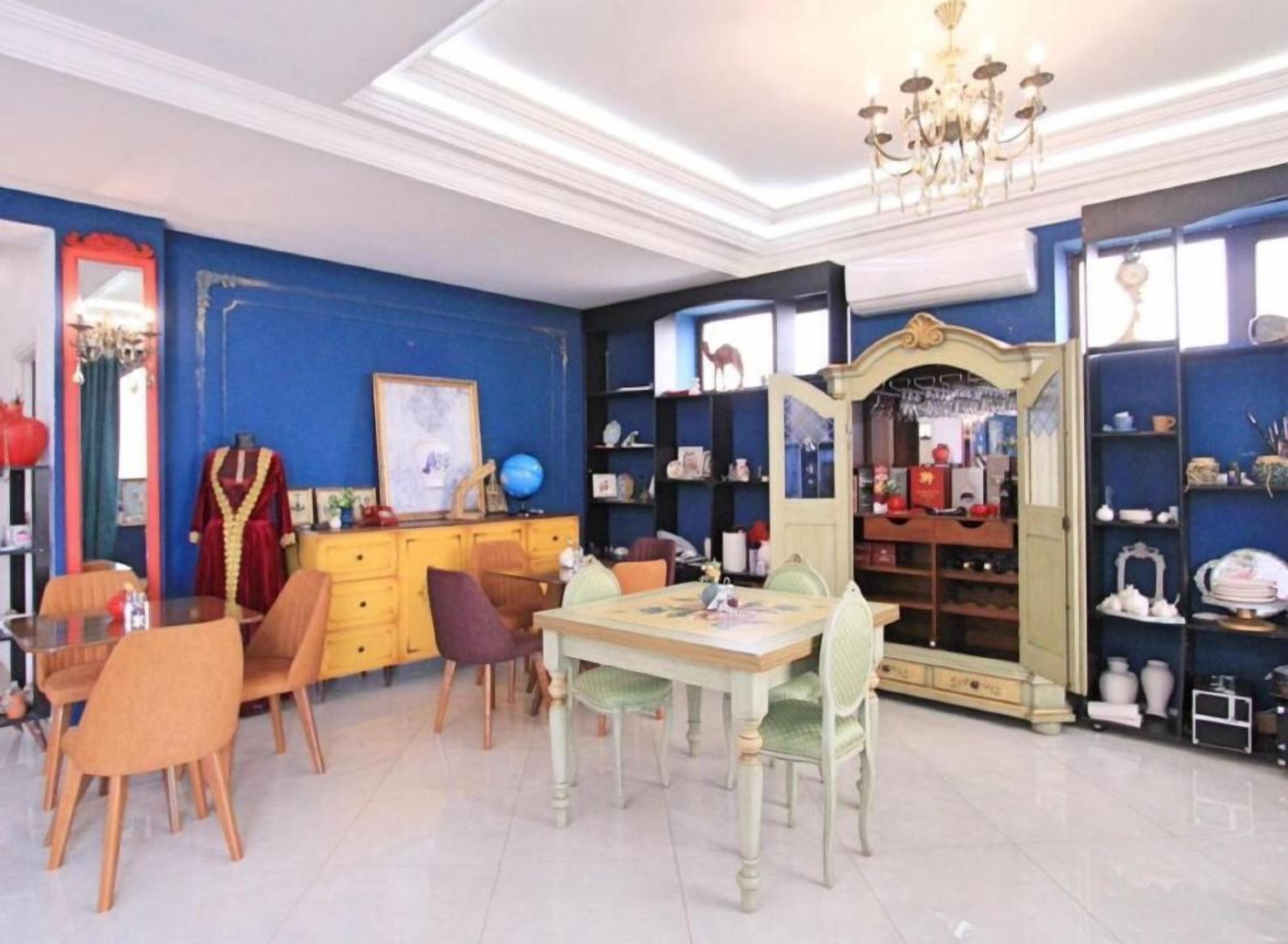 Un coin repas comprenant une table et des chaises, un miroir et des étagères où sont disposés divers objets.