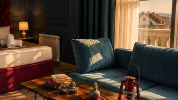 Une pièce comprenant un lit, un canapé, une table agrémentée d’objets décoratifs et une fenêtre donnant sur des immeubles.