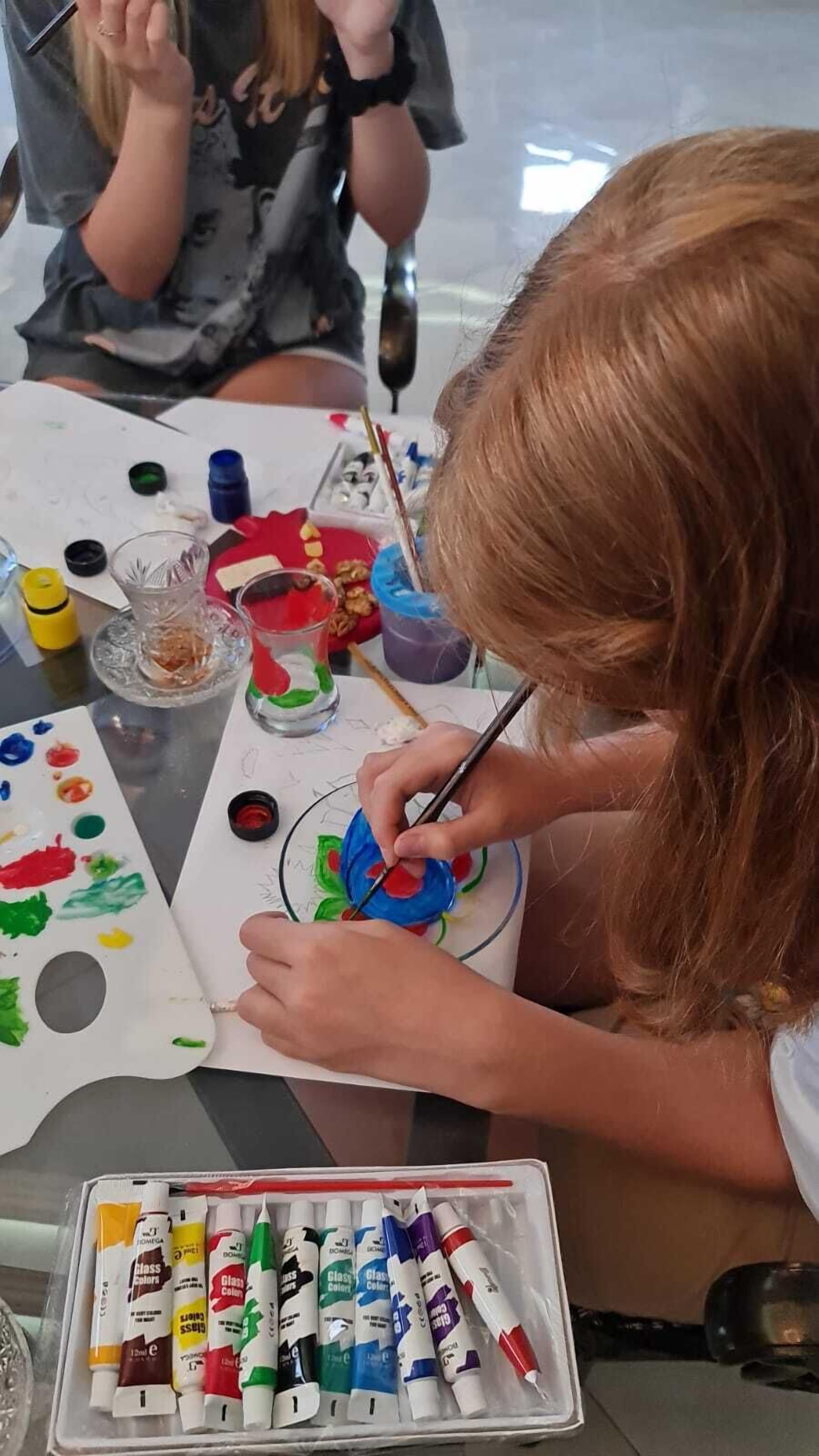 A person painting on a canvas with various art supplies on the table.