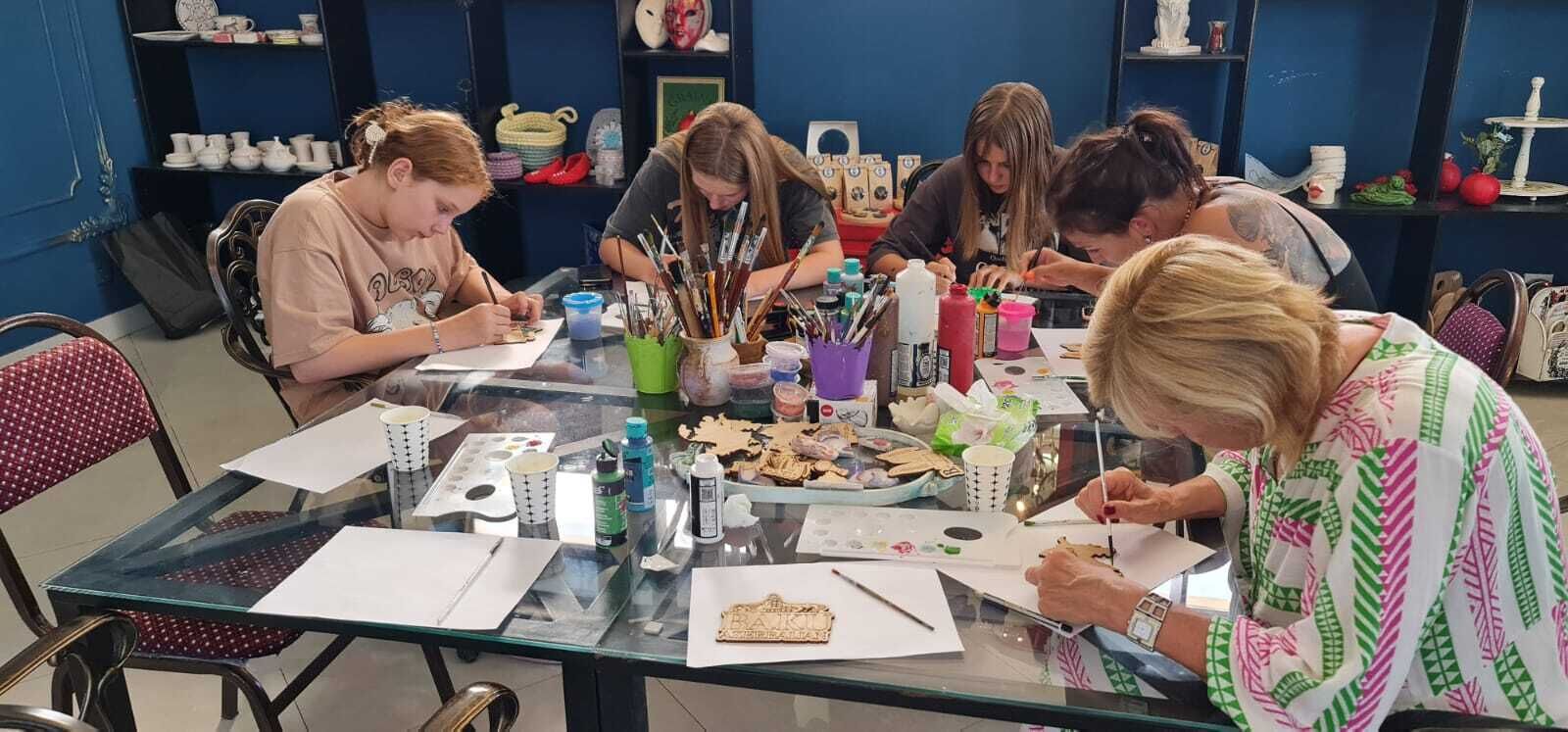Un gruppo di persone partecipa a un'attività creativa a un tavolo con materiali e forniture artistiche.