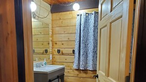L’intérieur d’une cabane en bois comprend une salle de bain, un lavabo et un espace douche.