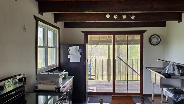 Une cuisine compacte équipée d’un réfrigérateur, d’une cuisinière et d’un évier, un balcon avec vue et une horloge au mur.