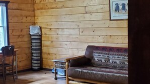 Un intérieur en bois avec un plafond haut, un canapé, un fauteuil et une petite table.