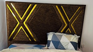 A bed with a quilted headboard, a patterned pillow, and a polka-dotted duvet. - OSIM HOMES (Arusha)
