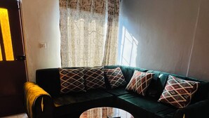 A living room with a sectional sofa, a round coffee table, and a patterned rug. - OSIM HOMES (Arusha)
