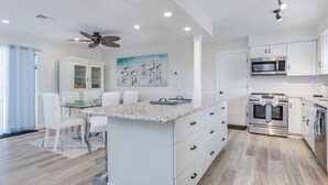 Una cocina moderna con armarios blancos, encimera de granito y electrodomésticos de acero inoxidable.