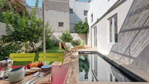 A poolside area with a table set for dining, a lounge chair, and a small pool.