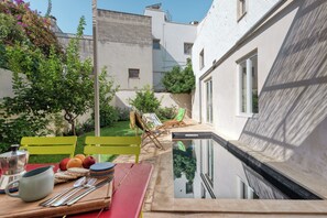 Ein Poolbereich mit Esstisch, Liegestuhl und kleinem Pool.