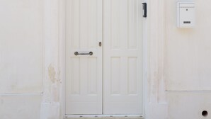 A white double door with a small window above it, set in a plain wall with a number '13' above the door.