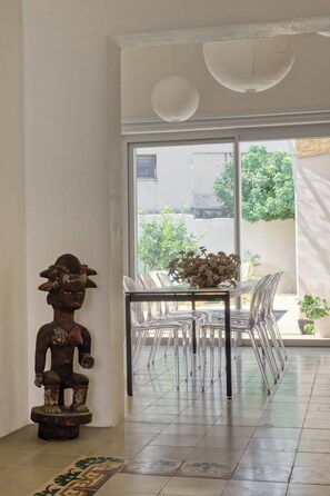 Ein Zimmer mit Esstisch, Stühlen, einer Zierstatue und Blick durch ein großes Fenster.
