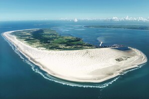 An aerial view of a coastal island with a sandy beach, a small settlement, and a clear blue sea. - TIDE4 Amrum No. 5 - Cute Tiny Loft for one person, 100m to the sea (Wittdün auf Amrum)