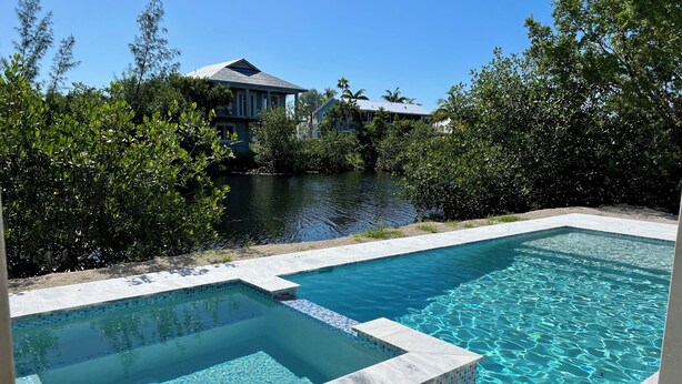 Una piscina rectangular con agua azul cristalina, rodeada por un solárium con baldosas.