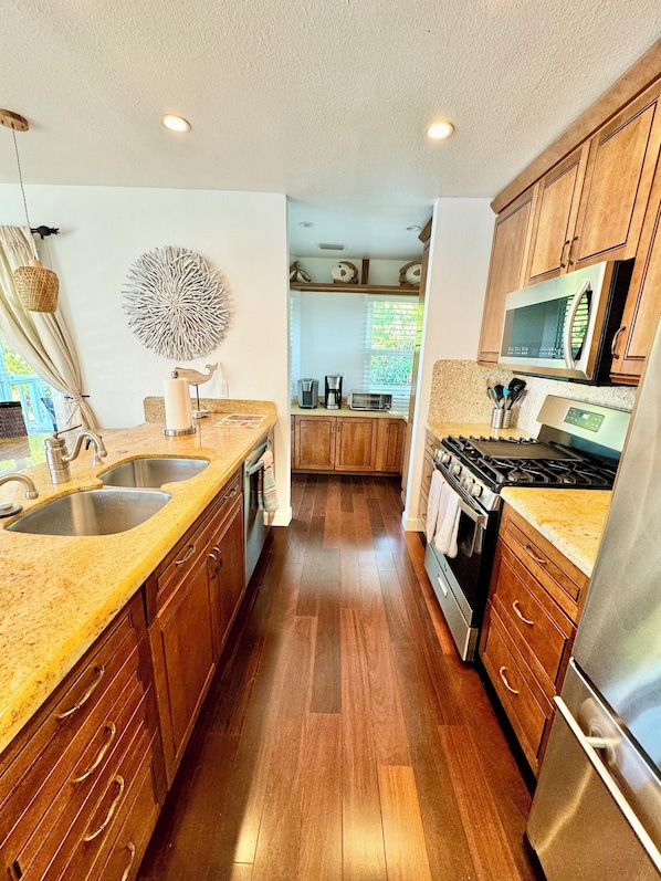 Eine moderne Küche mit Holzschränken, Edelstahlgeräten und einer Arbeitsplatte aus Granit.