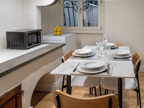 A modern kitchen with a microwave, a dining table set for four with white plates, glasses, and cutlery. - Palazzo Nori elegant & renovated apartment in the hearth of Florence (Firenze)