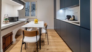 Cocina compacta con comedor, con encimera de mármol, electrodomésticos modernos y una pequeña mesa con sillas.