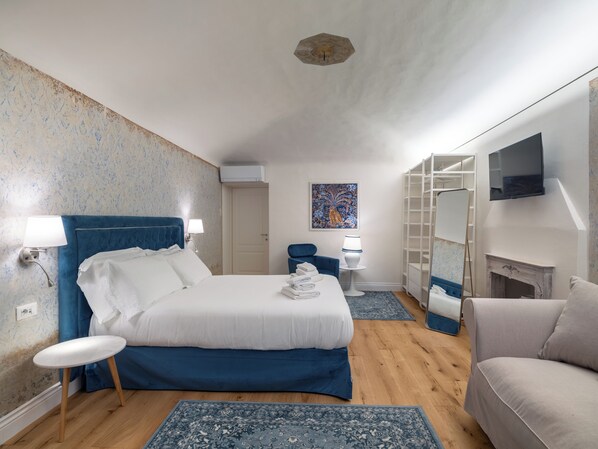 A bedroom with a bed, bedside tables, a chair, a TV, and a fireplace. - Palazzo Nori elegant & renovated apartment in the hearth of Florence (Firenze)