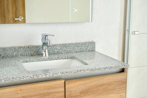 Bathroom features a granite countertop, stainless steel faucet, and wooden cabinetry.