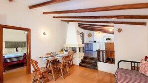 A cozy room with a wooden dining table, chairs, and a bed with a striped bedspread. - Charming stone trullo with sea access (house F) (Castro)