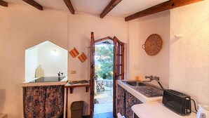 A compact kitchen with a sink, a toaster, and a small window leading to a garden. - Charming stone trullo with sea access (house F) (Castro)