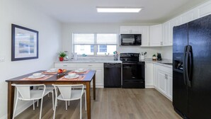 Una cucina moderna con mobili bianchi, un frigorifero nero, un forno a microonde e un fornello.