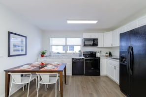 Una cocina moderna con armarios blancos, un refrigerador negro, un microondas y una estufa.
