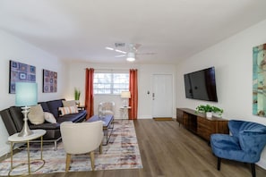 Una sala de estar moderna con un sofá, sillones, una mesa de centro y un televisor.